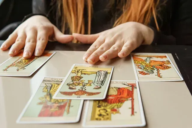 Una mujer está sentada en una mesa jugando a las cartas del tarot.