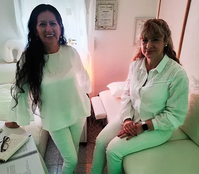 Dos mujeres con camisas blancas están paradas una al lado de la otra en una habitación.