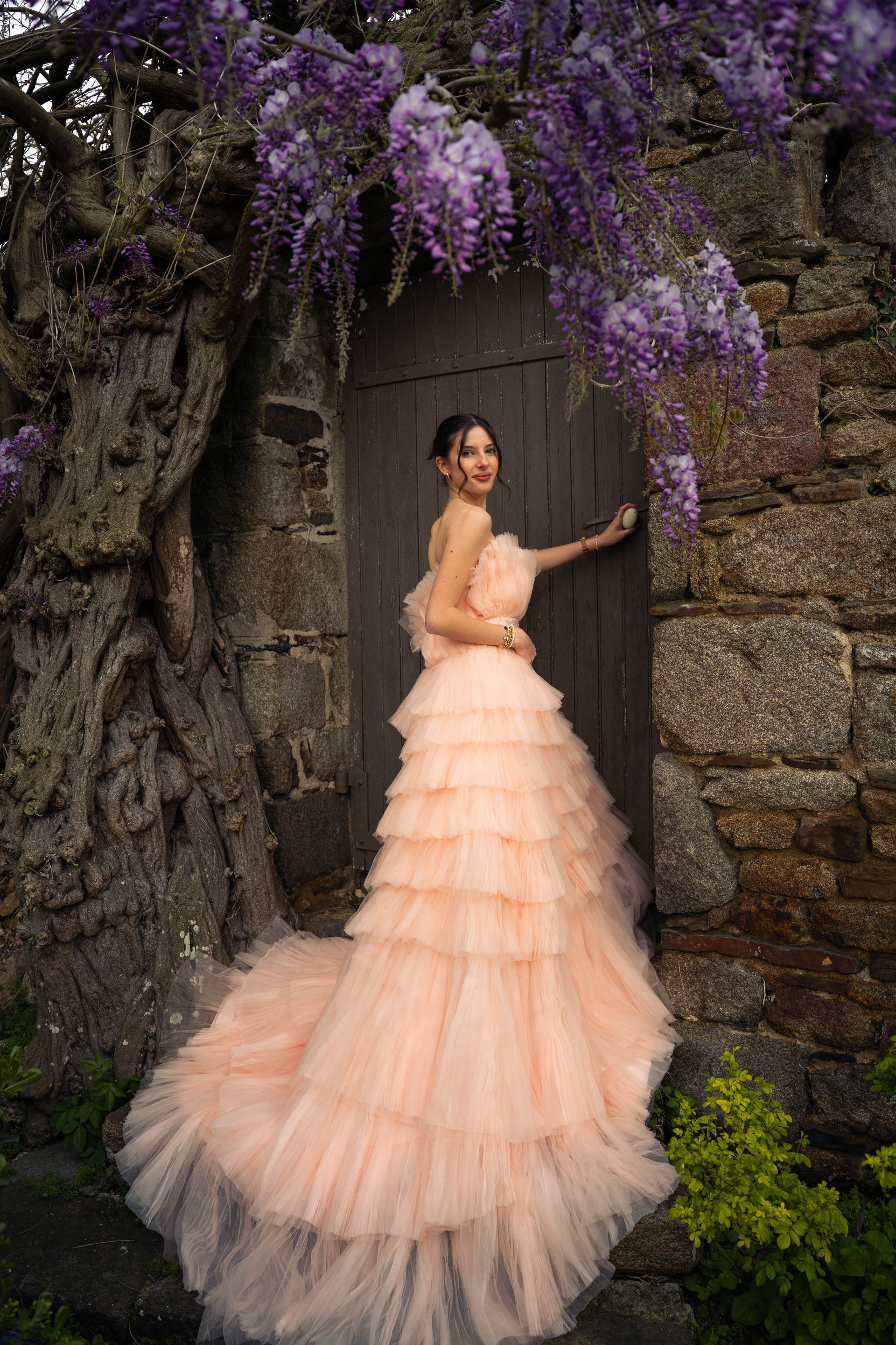 Une femme dans une longue robe rose appuyée contre un rocher