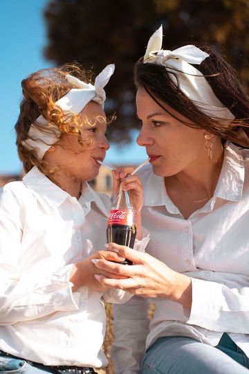 Une femme et un enfant partagent un soda, tous deux vêtus de.