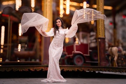 Une femme en robe blanche se tient devant un manège.