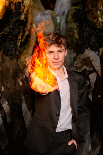 Un homme en costume tient une boule de feu dans sa main.
