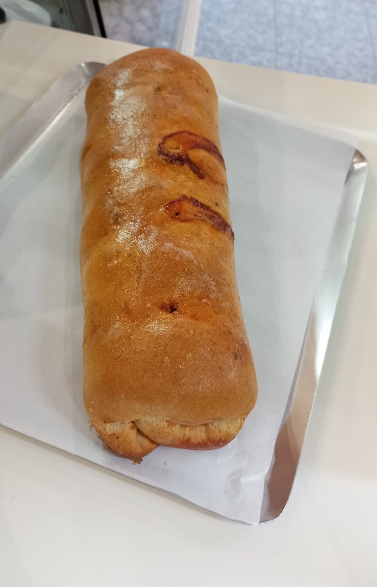 Un panecillo dorado sobre una servilleta blanca, al lado de un cuchillo en una bandeja.