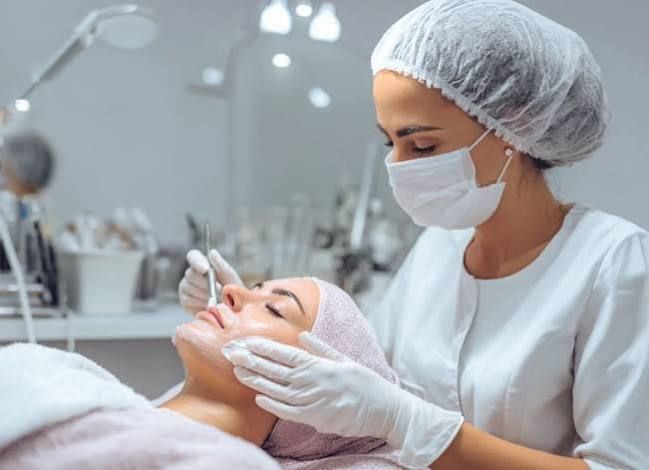 Esteticista realizando un tratamiento facial a una clienta en una luminosa clínica de spa.