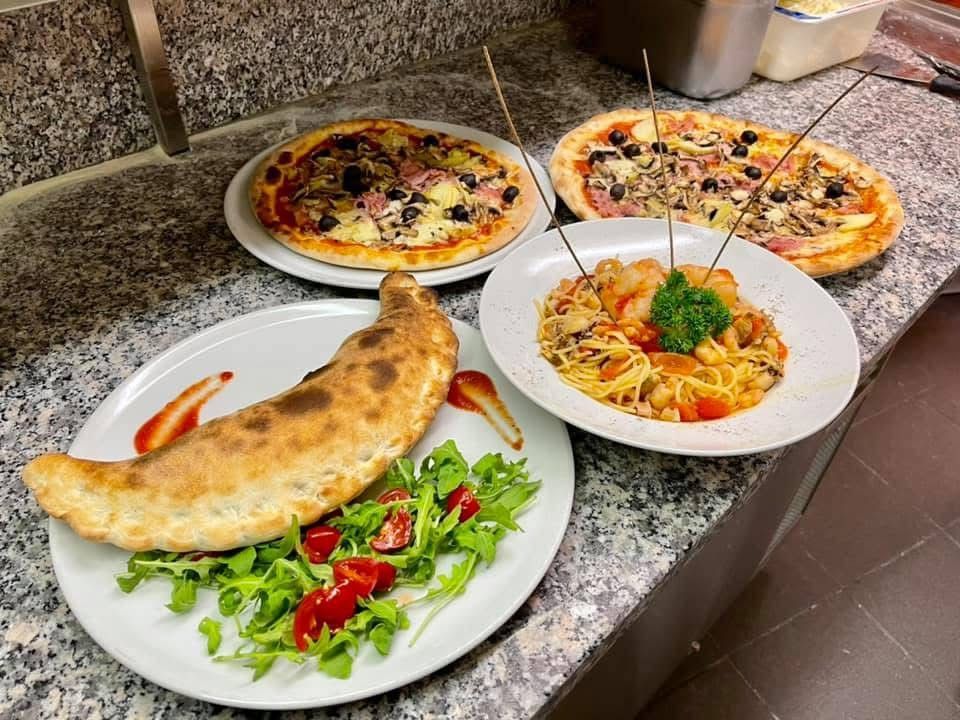 Ein Teller Nudeln mit Erbsen und Speck auf einem Tisch.