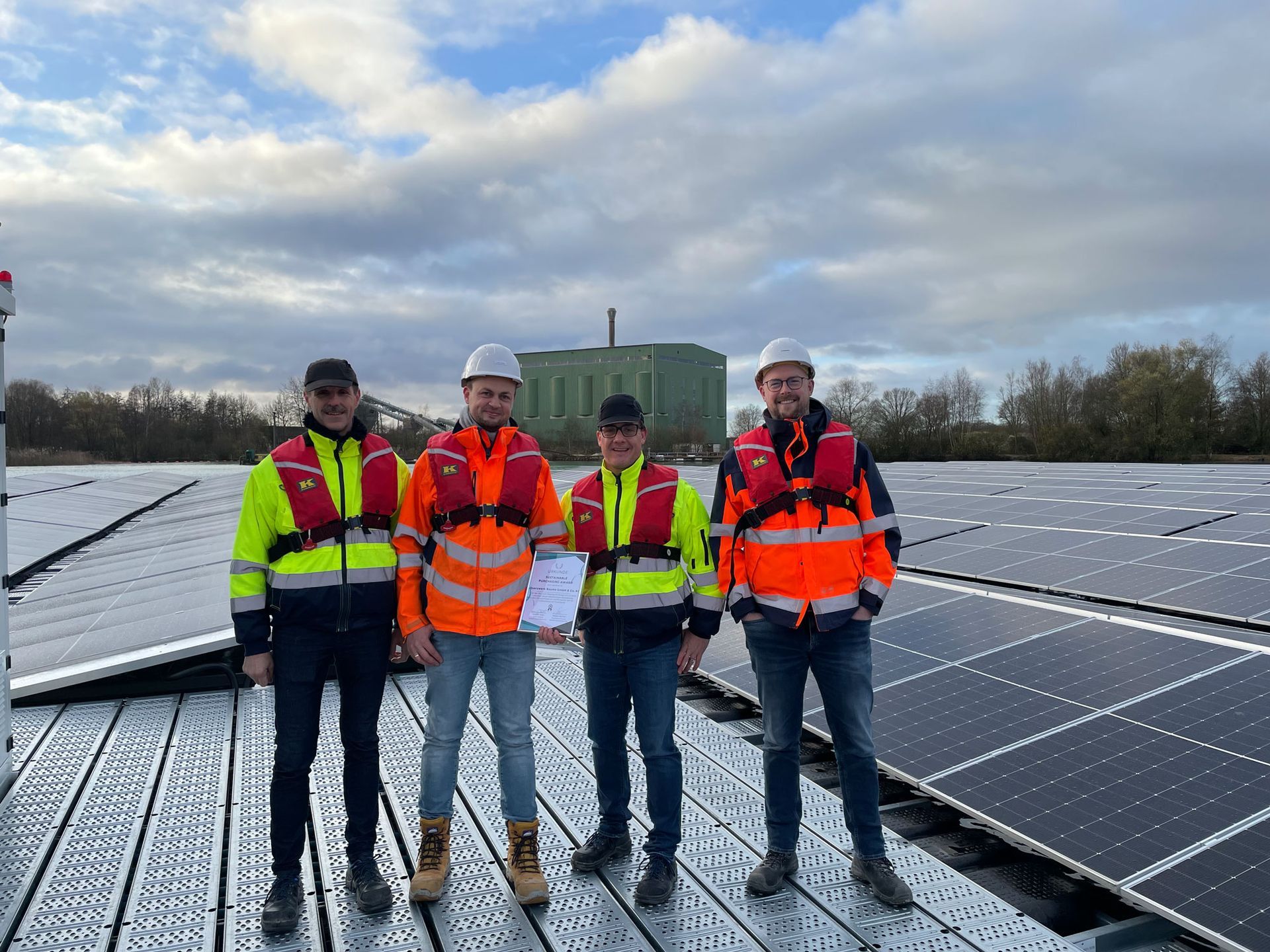 Eine Gruppe von Männern steht auf einem Dach mit Solarmodulen.