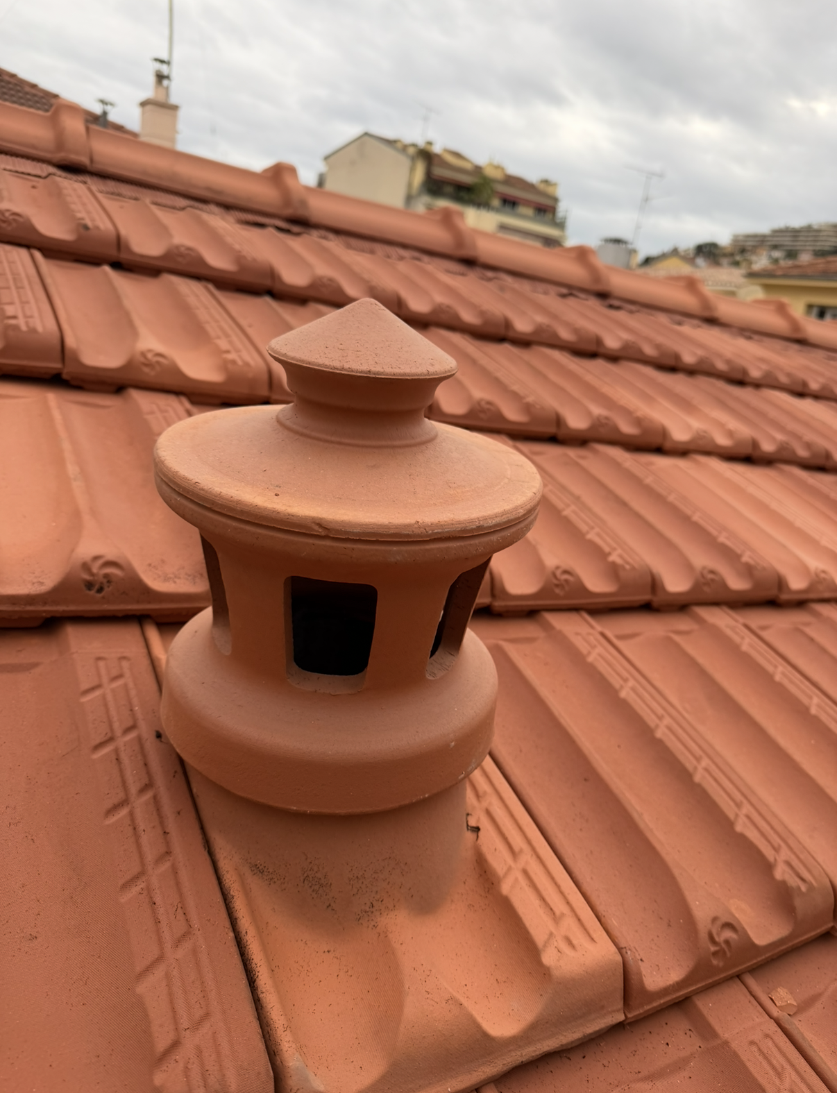 Grille d'aération en tuile de terre cuite avec capuchon décoratif.
