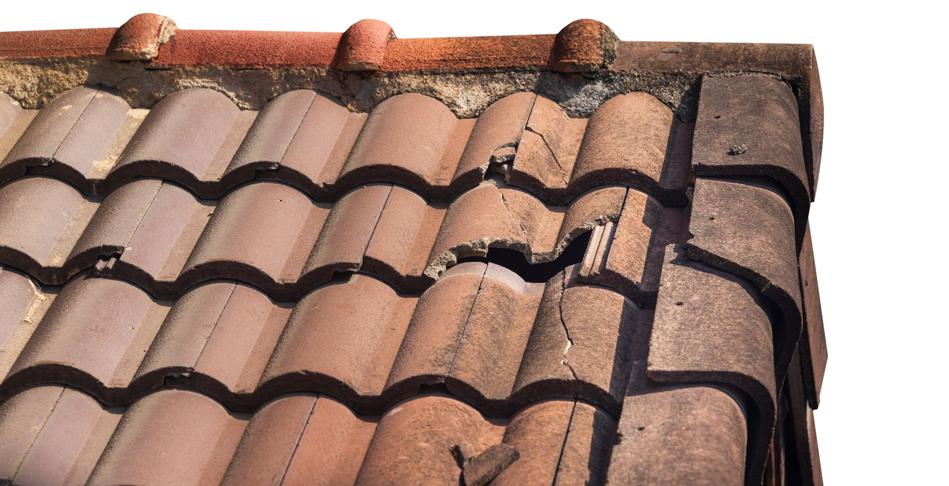 Toit en tuiles de terre cuite endommagé, montrant des tuiles fissurées et cassées près du bord.