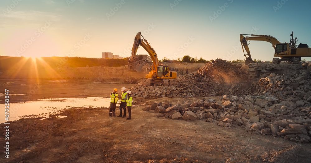 Cantiere edile al tramonto con escavatori, macerie e due operai con giubbotti di sicurezza.