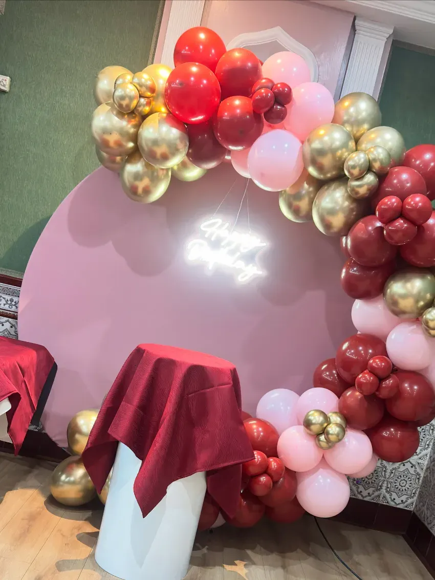Fondo de globos rosa pastel con globos dorados, rojos y blancos en una exhibición de eventos