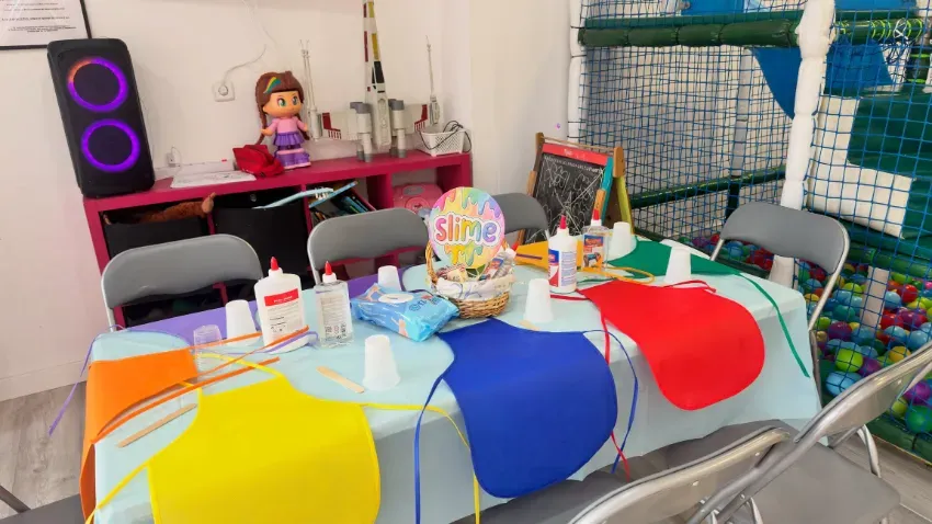 Mesa de postres decorada con globos en un local de fiestas con detalles en azul, blanco y dorado.