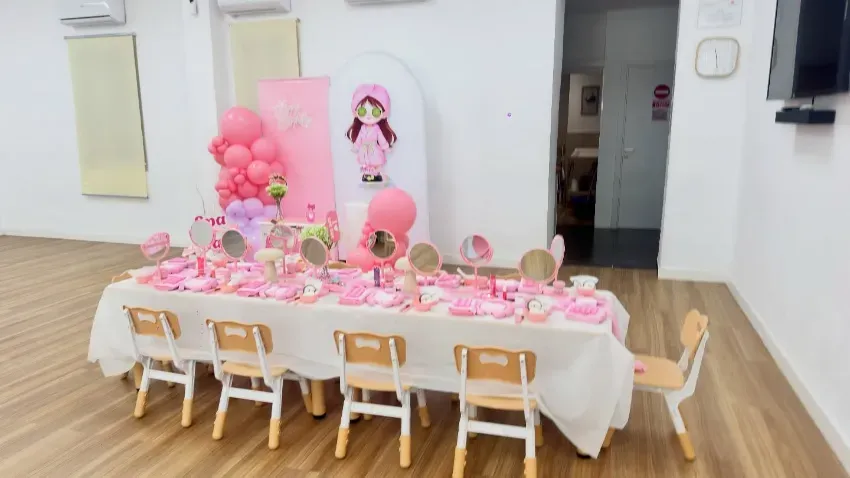Mesa de postres decorada con globos en un local de fiestas con detalles en azul, blanco y dorado.