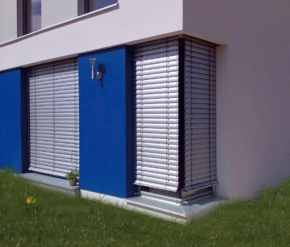 Ein blau-weißes Gebäude mit weißen Jalousien an den Fenstern