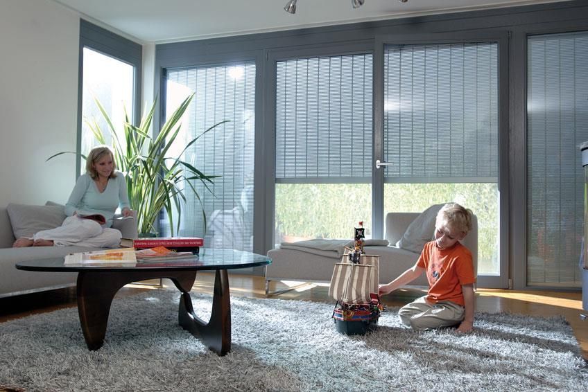 Eine Frau sitzt auf einem Sofa, während ein Junge in einem Wohnzimmer mit einem Spielzeugschiff spielt.