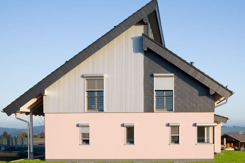 Ein rosa-weißes Haus mit einem schwarzen Dach