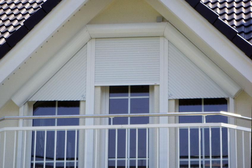 Ein Haus mit einem Balkon und einem Fenster mit Fensterladen
