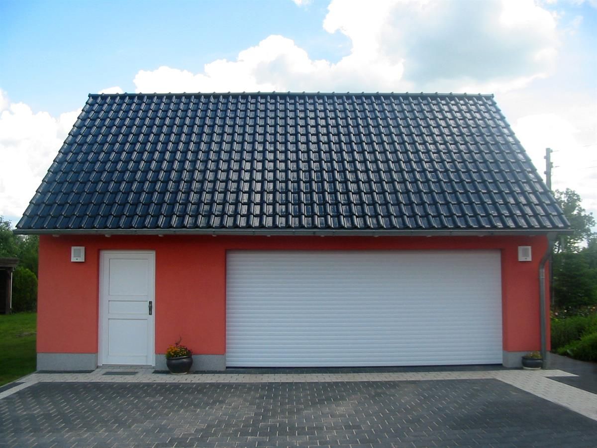 Eine rote Garage mit weißem Tor und schwarzem Dach