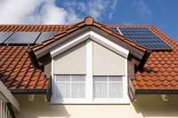 Ein Haus mit rotem Ziegeldach und Solarzellen auf dem Dach.