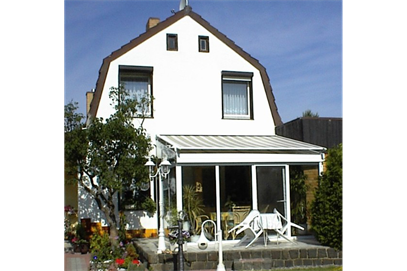 Ein weißes Haus mit einem braunen Dach und einer großen Veranda