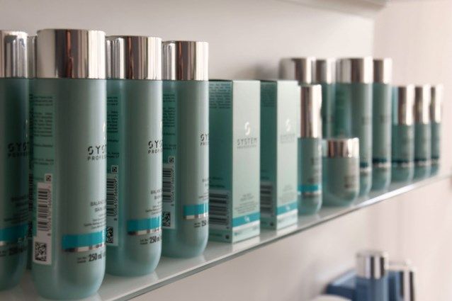Ein Regal voller hellblauer Haarpflegeprodukte mit silbernem Logo im Friseursalon Meyer & Marks by Anja Kagel in Werder.