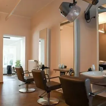 Innenansicht des Friseursalons Meyer & Marks by Anja Kagel mit braunen Ledersesseln, Wandspiegeln und Haarwaschplatz.