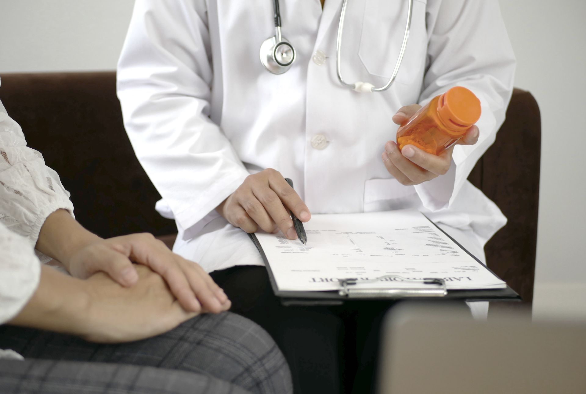 Ernährungsberater hält Medikamentenflasche in der Hand und schreibt auf Klemmbrett, während er einen Patienten berät.