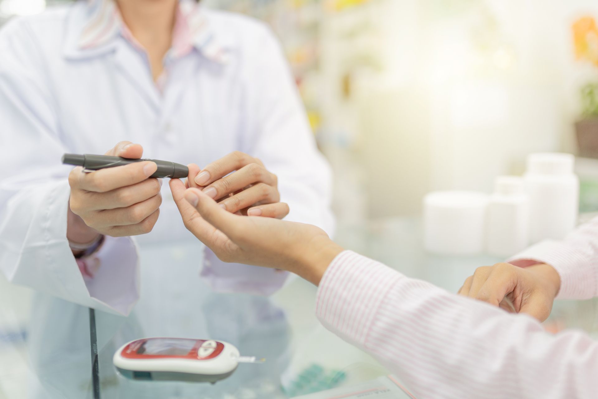 Ernährungsberater überprüft den Blutzucker des Patienten mit einem Blutzuckermessgerät. Weisser Kittel, helle Umgebung.