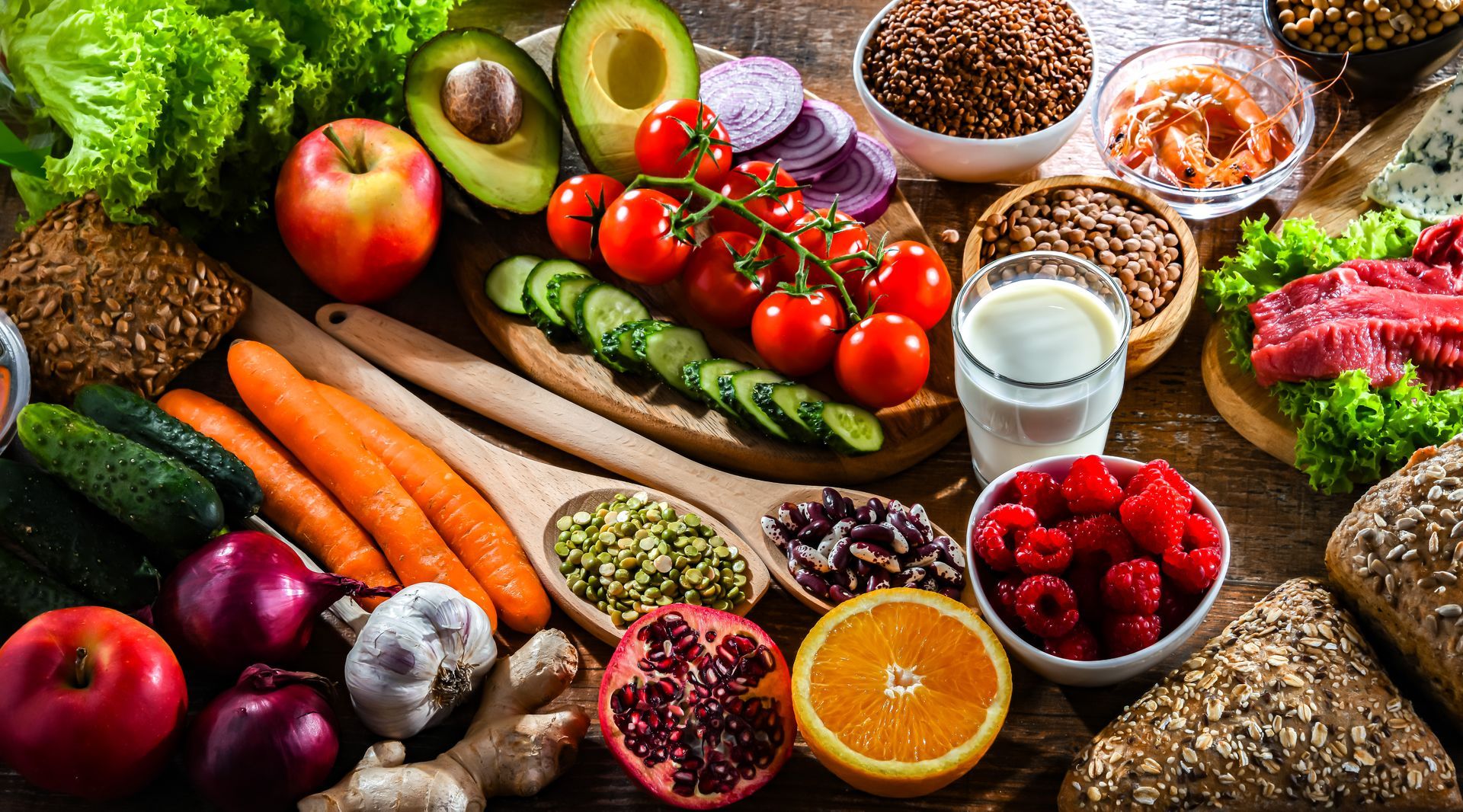 Bunte Auswahl an gesunden Lebensmitteln, darunter Gemüse, Obst, Samen, Brot, Fleisch und Milchprodukte.