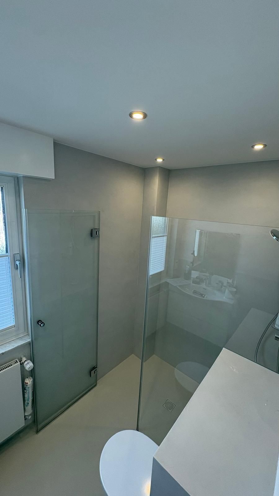 Modernes Badezimmer mit Glasdusche, grauen Wänden, weißen Armaturen und Deckeneinbauleuchten