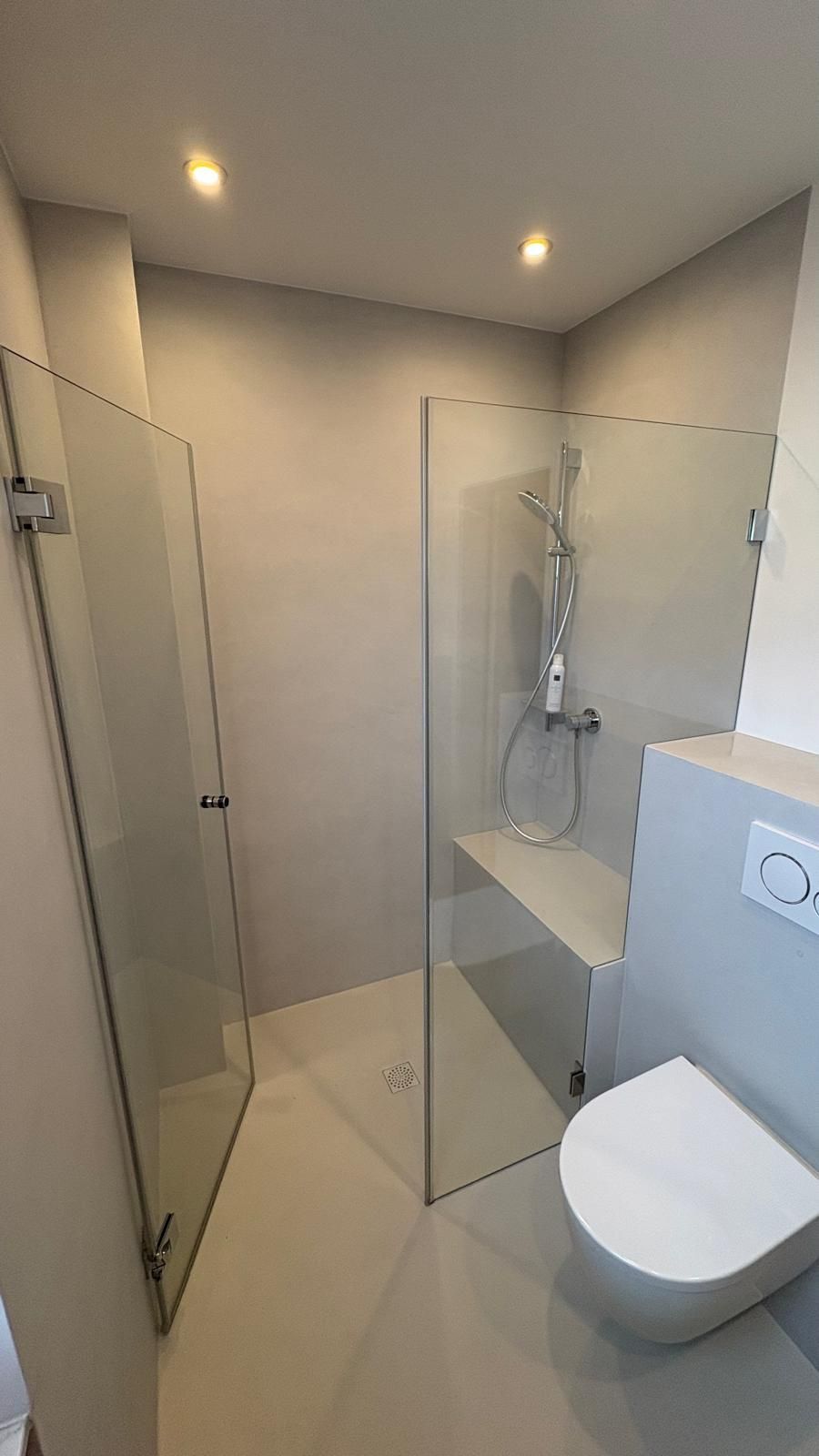Modernes Badezimmer mit Glasdusche, weißen Wänden und wandhängendem WC