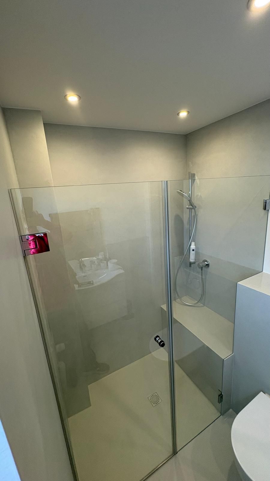 Moderne Badezimmerdusche mit Klarglastüren, Chromarmaturen und hellgrauen Wänden