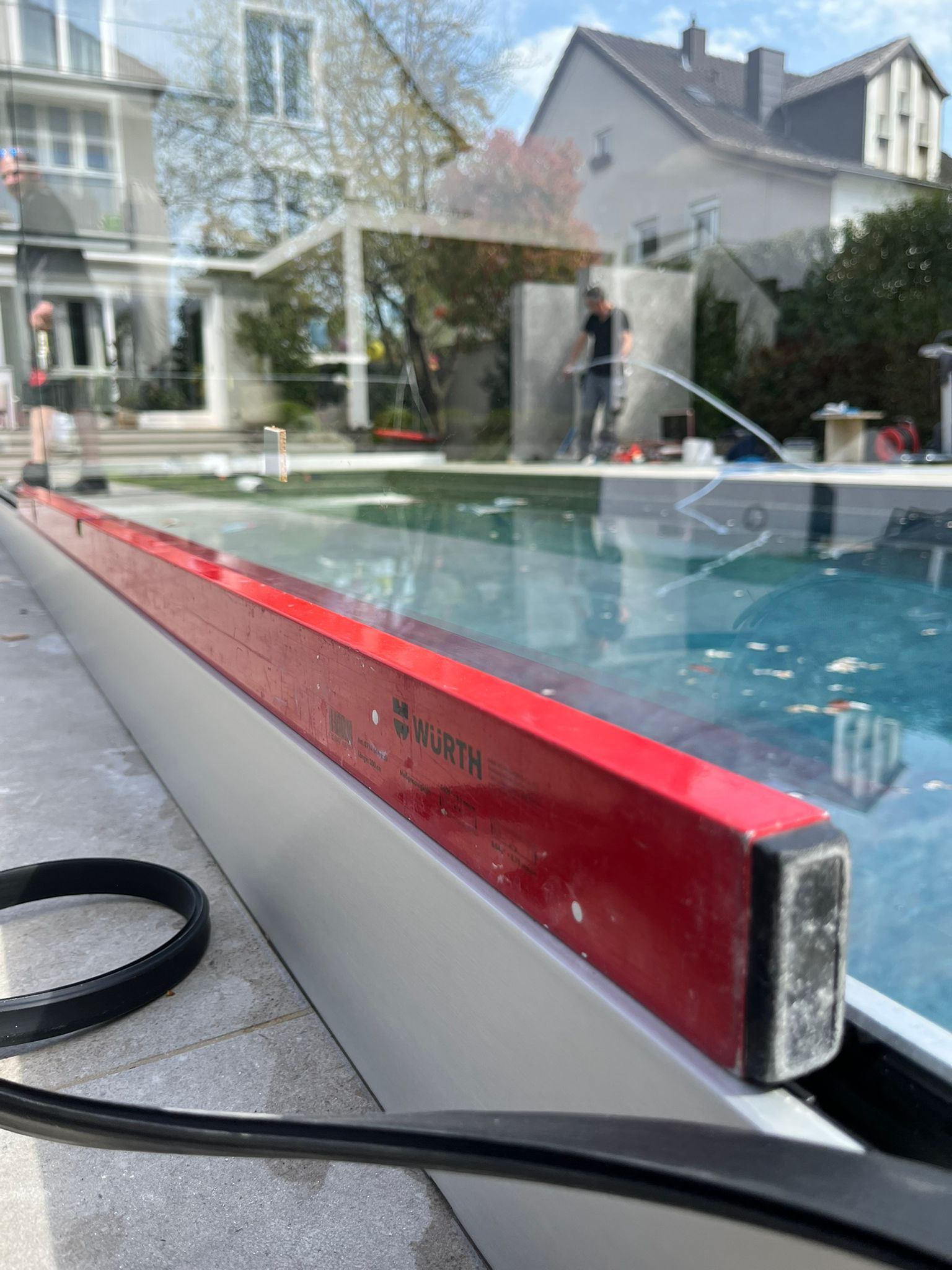 Swimmingpool im Garten mit rotem Glasrand und im Wasser gespiegeltem Haus