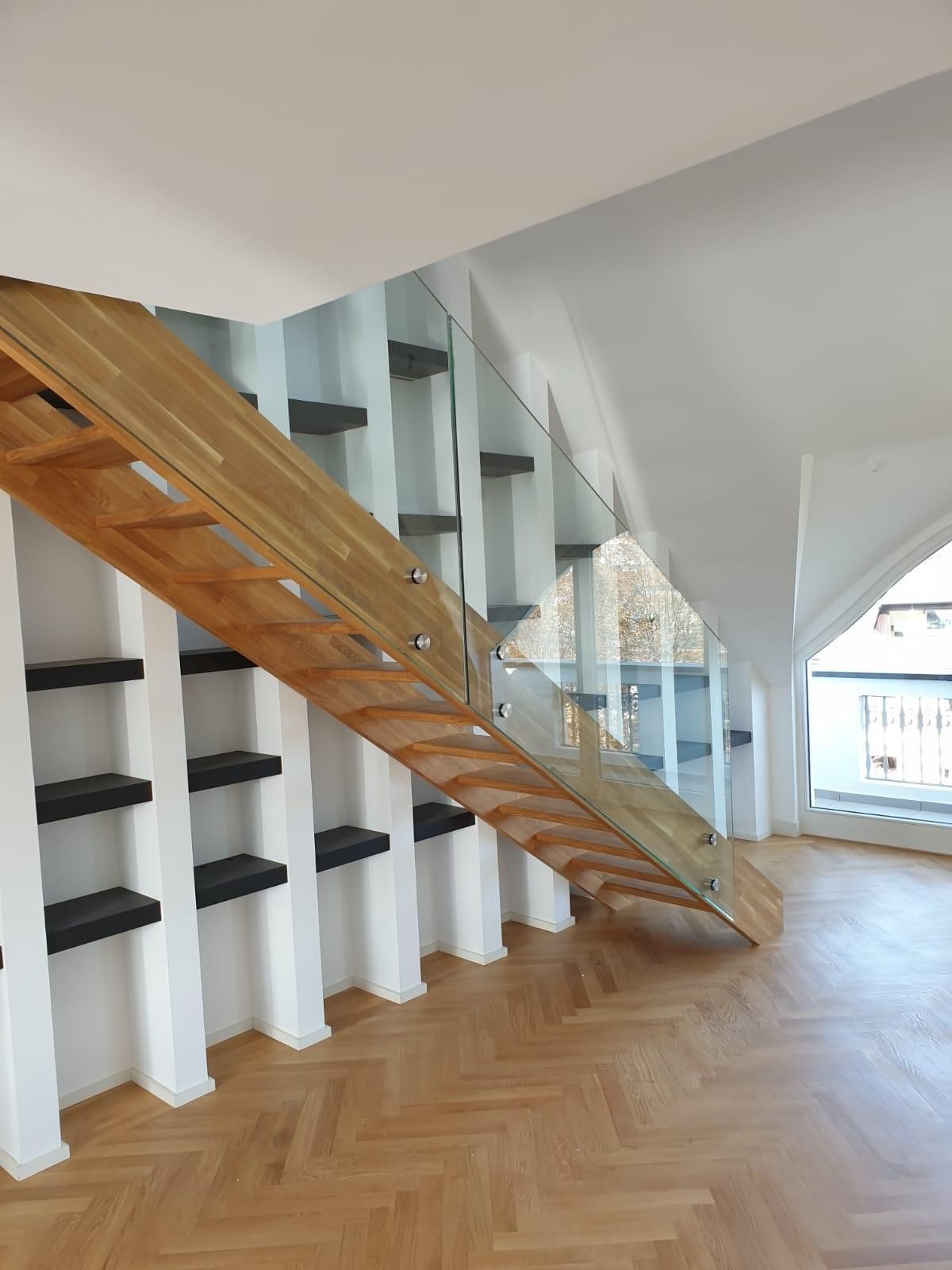 Eine Holztreppe mit Glasgeländer in einem leeren Raum