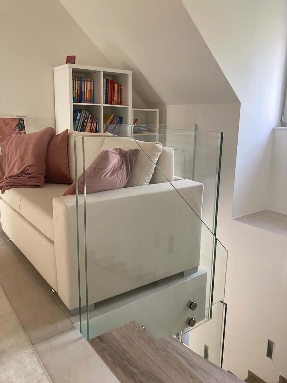 Ein Wohnzimmer mit einer weißen Couch und einem Glasgeländer.