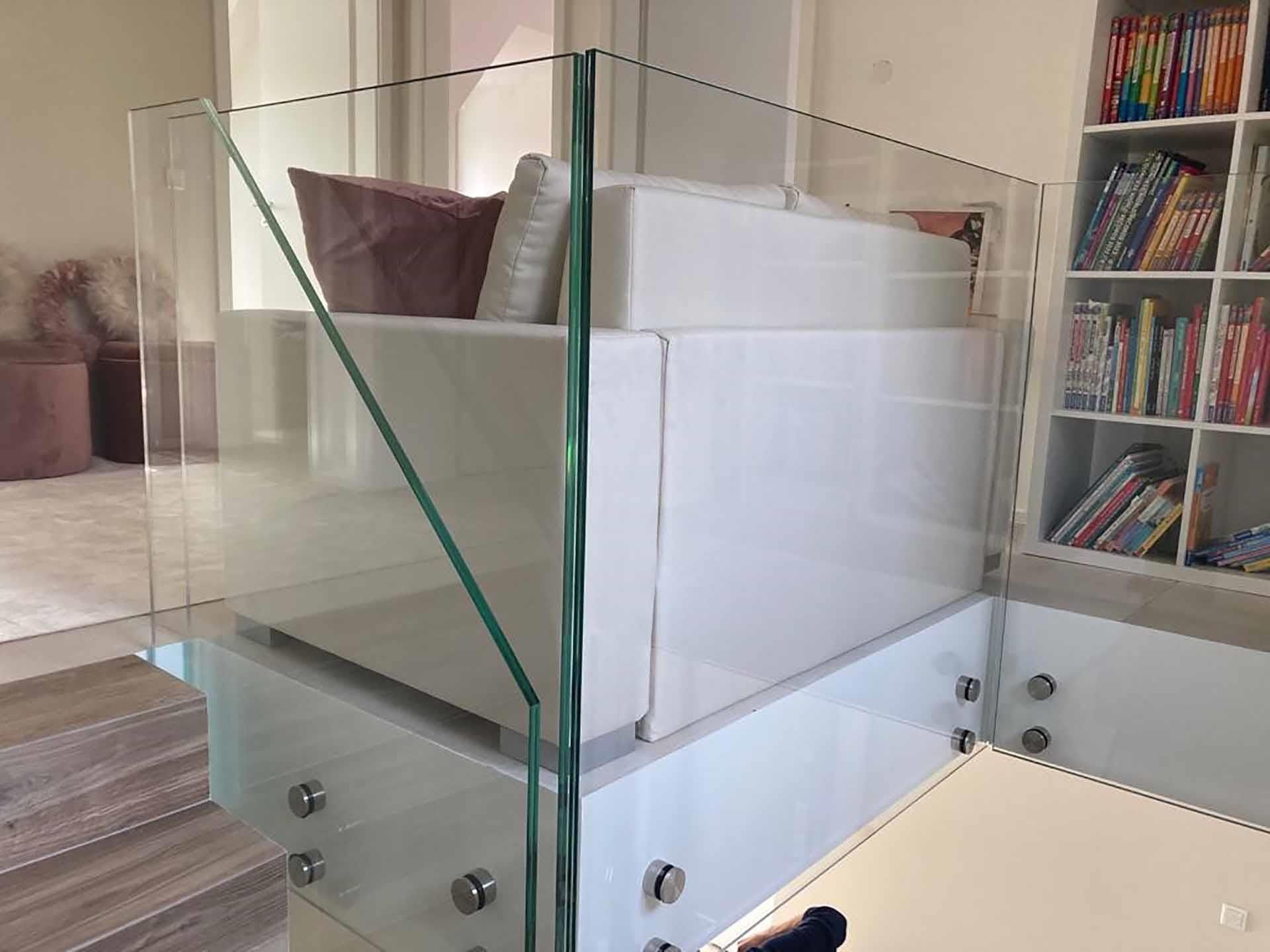 Eine Treppe mit Glasgeländer und einer Couch im Hintergrund