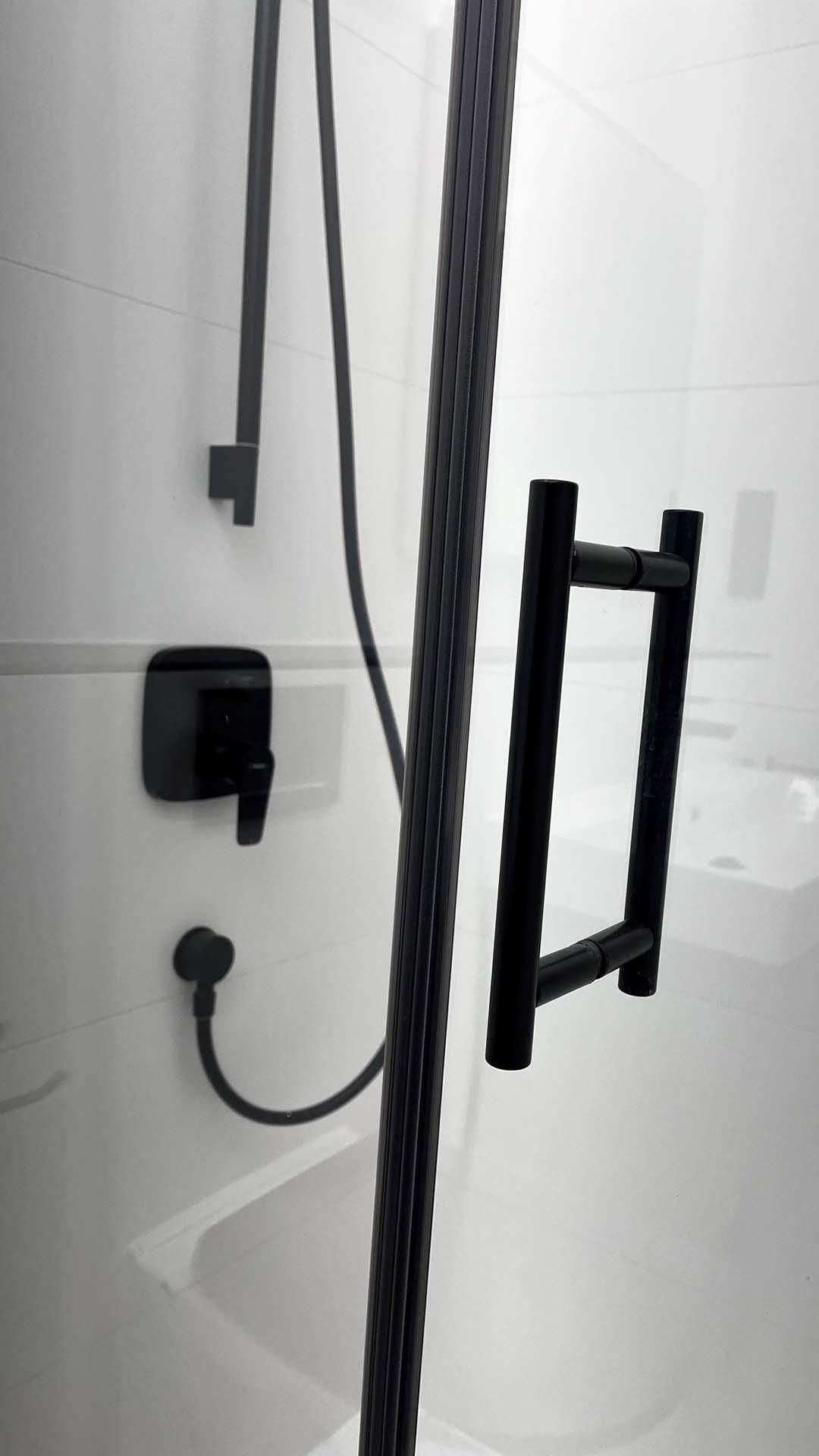 Ein Badezimmer mit einem schwarzen Duschkopf und einem schwarzen Handtuchhalter