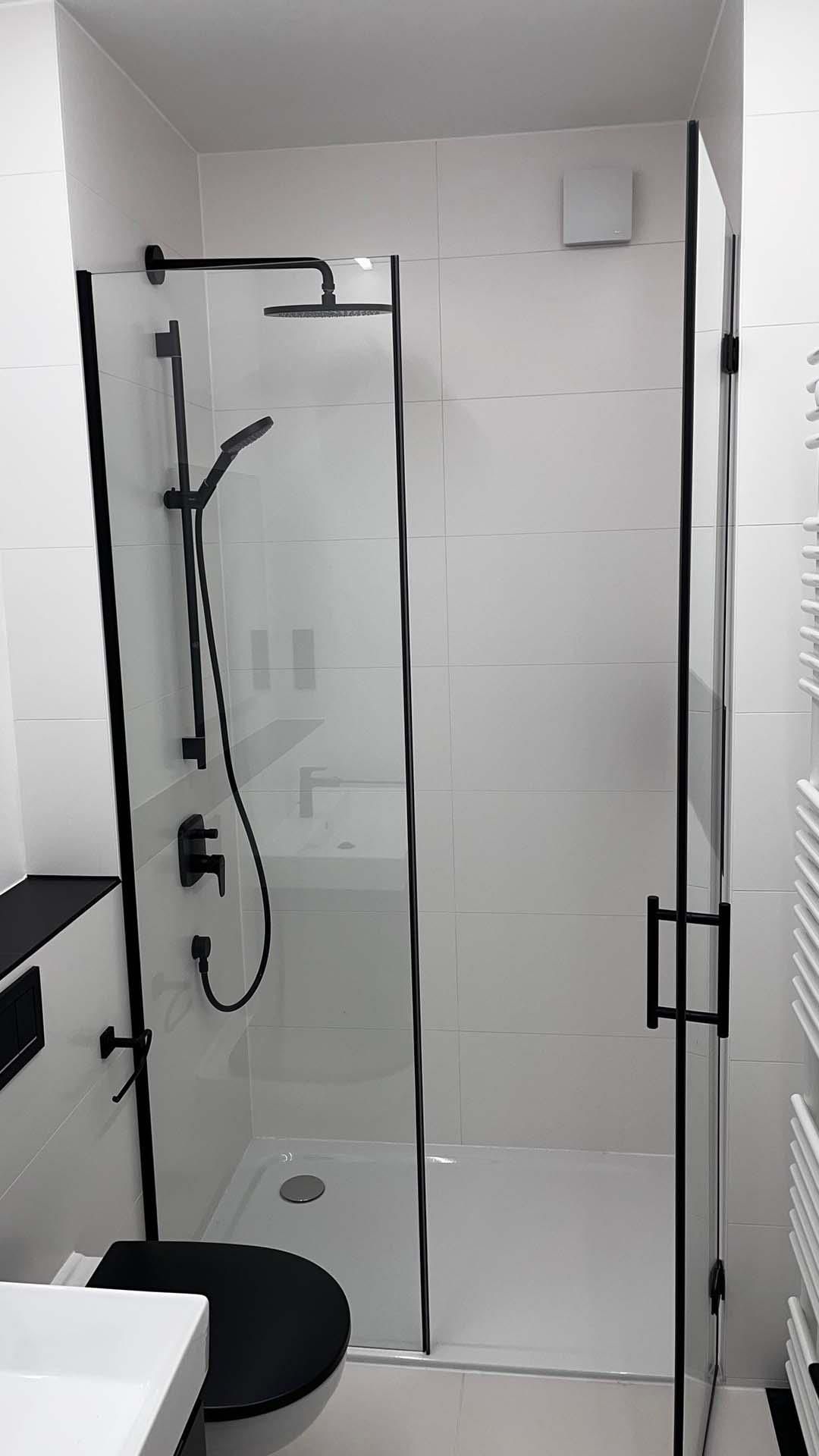 Ein Badezimmer mit ebenerdiger Dusche, Toilette, Waschbecken und Handtuchhalter.