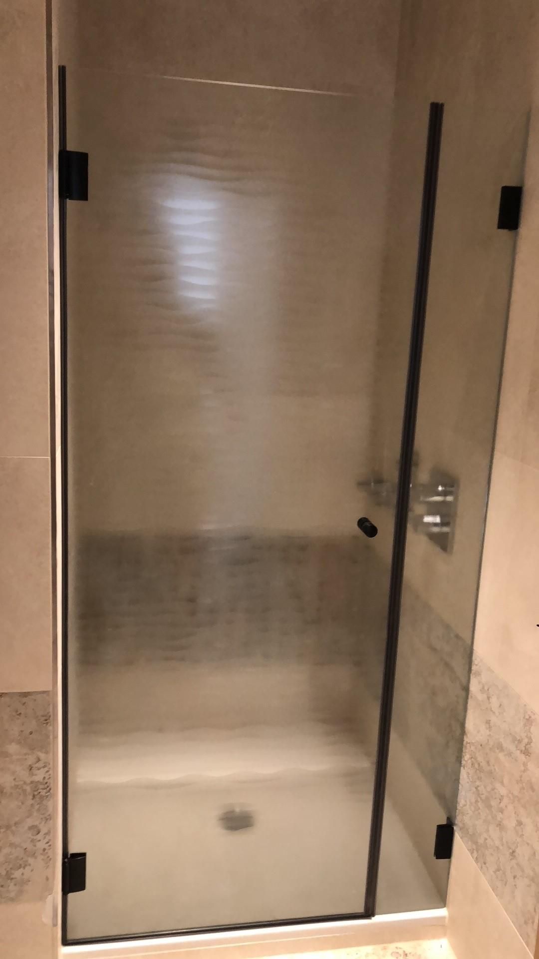 Ein Badezimmer mit ebenerdiger Dusche mit klarer Glastür