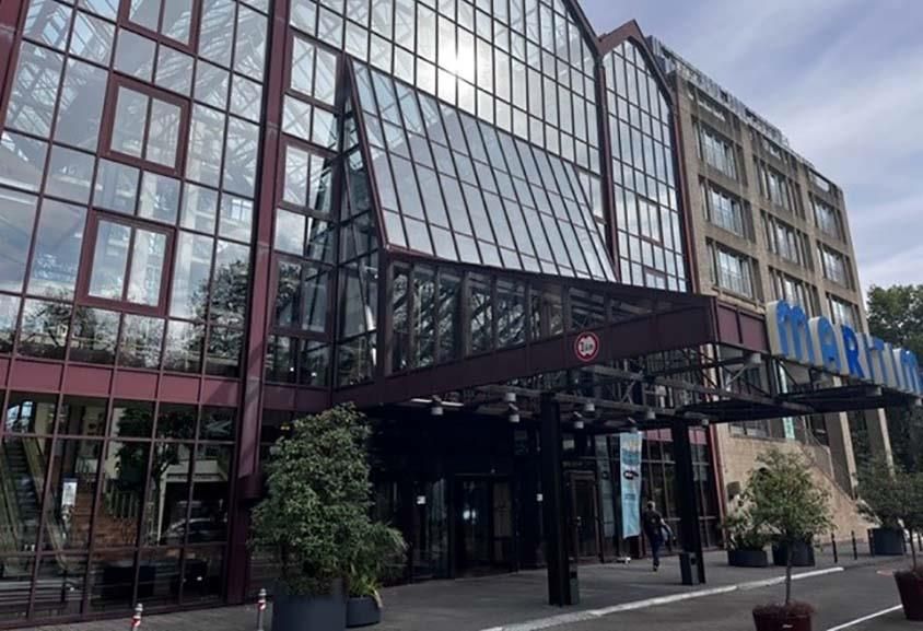 Ein großes Gebäude mit vielen Fenstern und Bäumen davor.