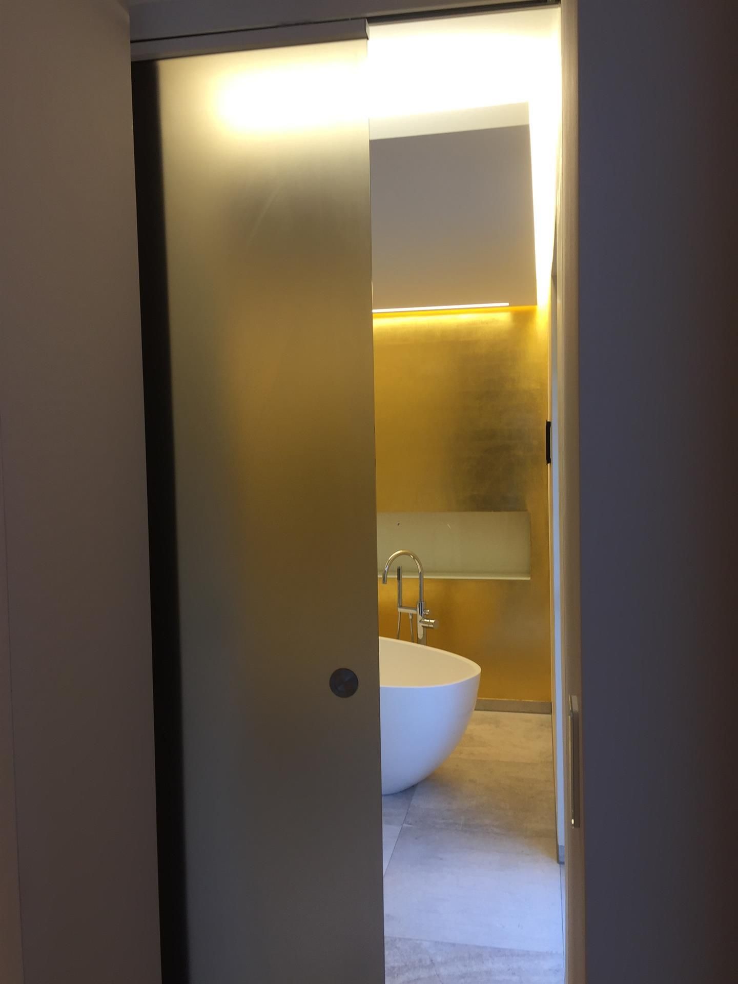 Ein Badezimmer mit Glasschiebetür und Badewanne