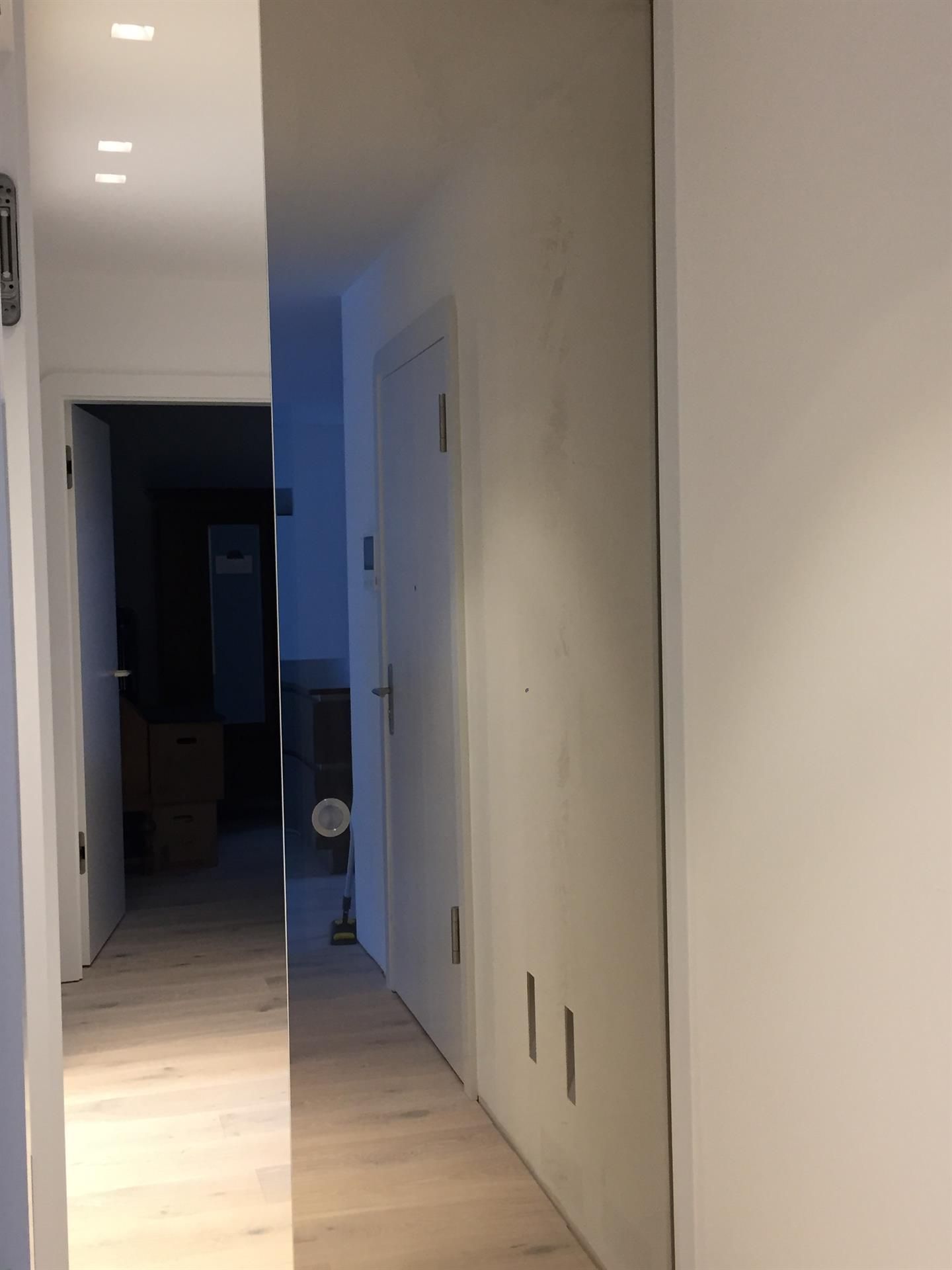 Ein langer Flur mit weißen Wänden und Holzböden