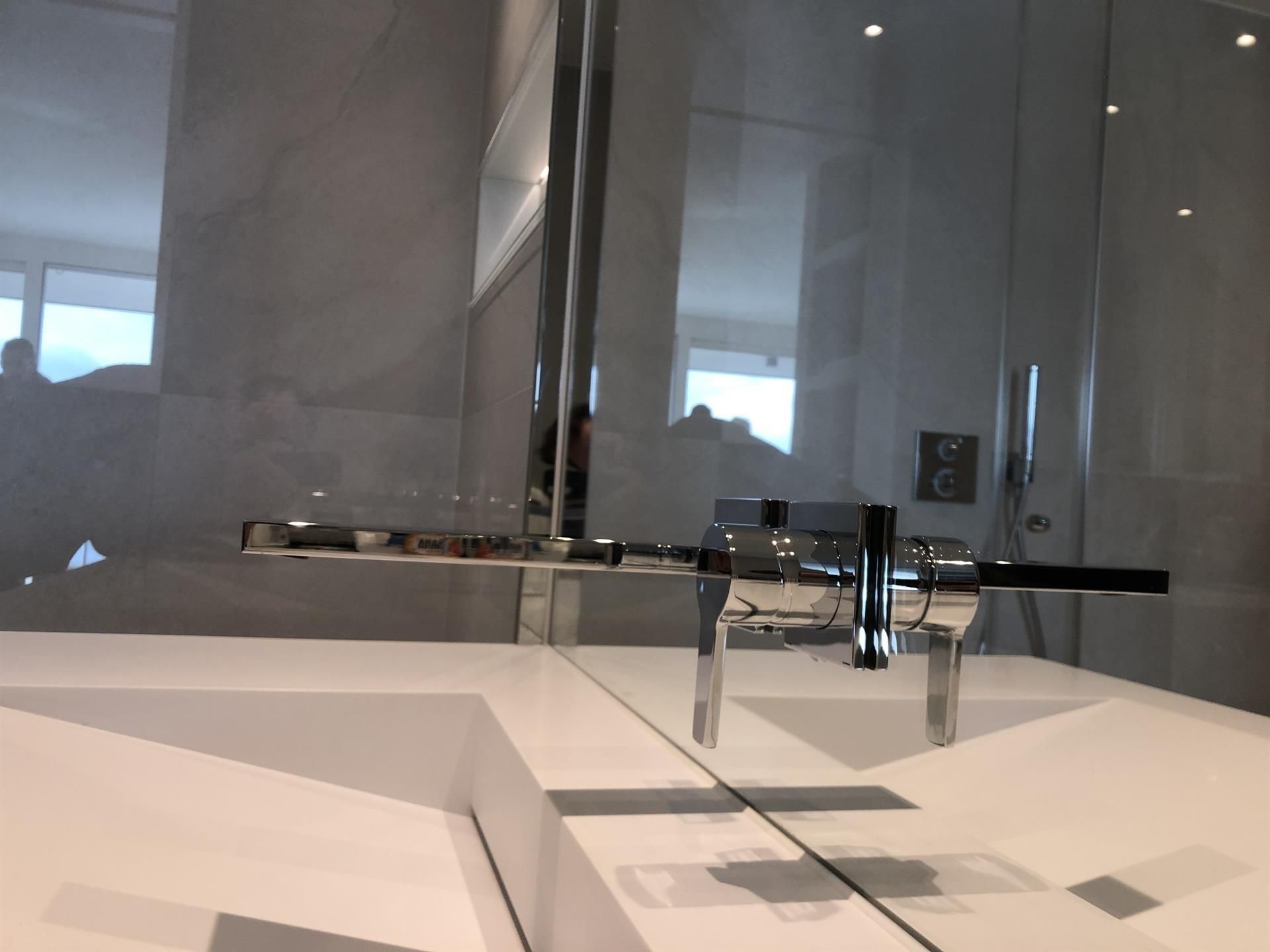 Ein Waschbecken mit Wasserhahn und Spiegel