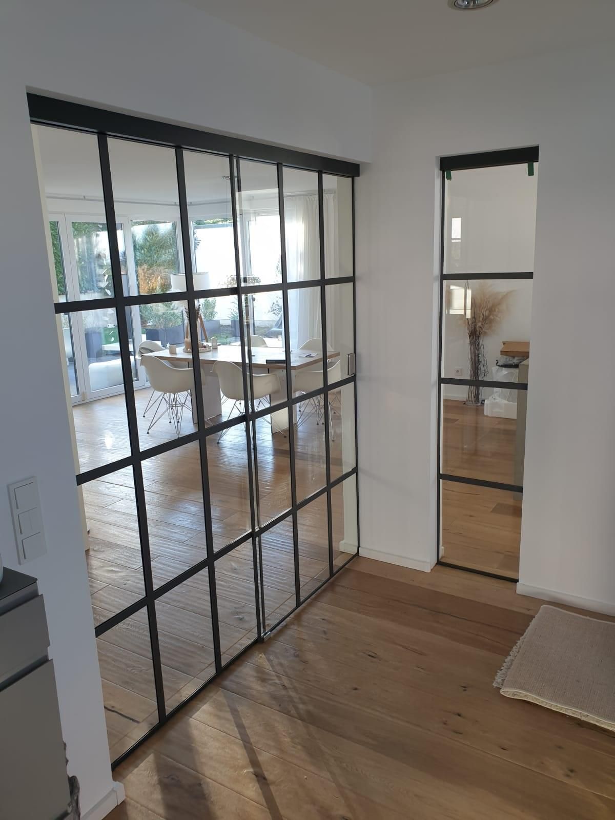 Ein Flur mit Glasschiebetüren, die zu einem Esszimmer führen