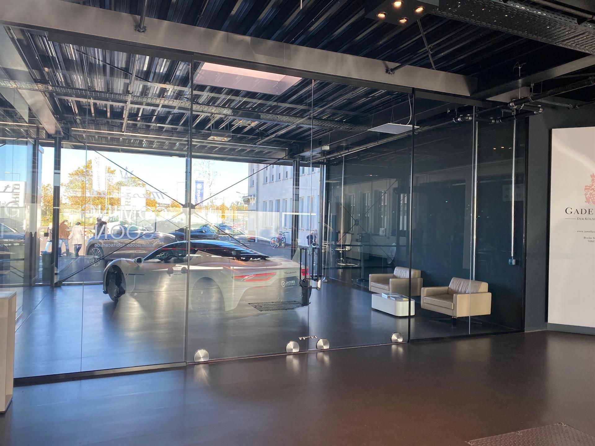 Ein Auto ist vor einer Glaswand geparkt