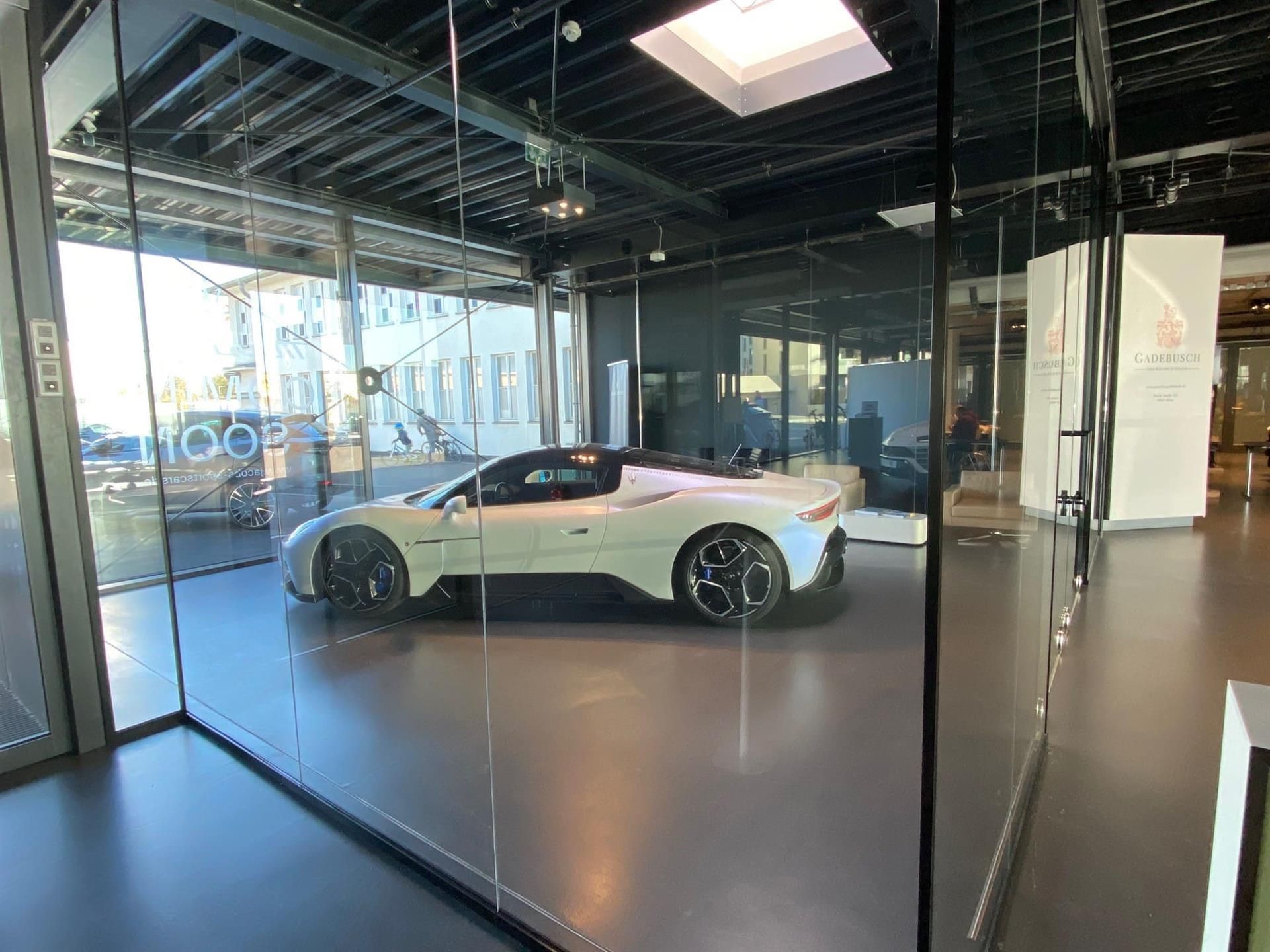 Ein weißer Sportwagen steht in einem gläsernen Ausstellungsraum