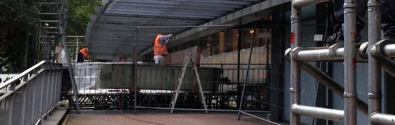 Ein Mann steht auf einer Leiter vor einem im Bau befindlichen Gebäude.