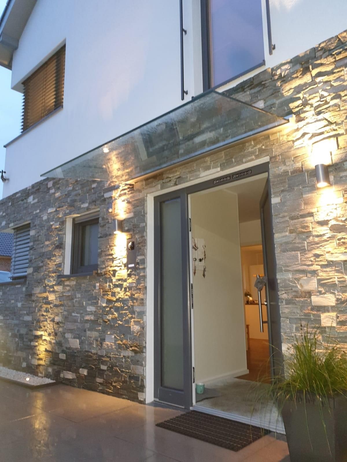 Die Eingangstür eines Hauses ist mit einem Glasdach versehen