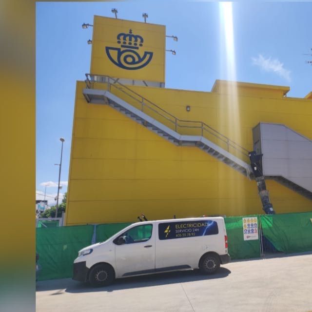 Una camioneta blanca está estacionada frente a un edificio amarillo