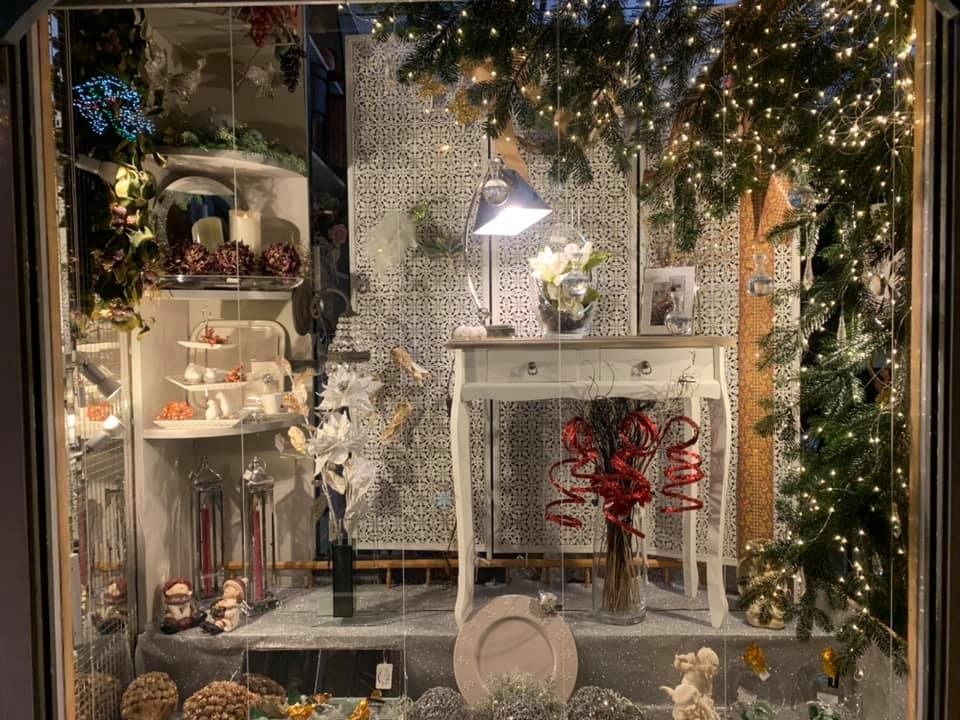 Escaparate: Decoración navideña, mesa blanca, flores, adornos, guirnalda, luces.