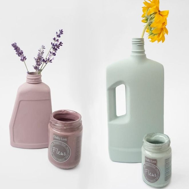 Dos botellas de plástico pintadas reutilizadas como jarrones, con flores, frascos de pintura.